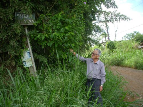 「オオウラ（大浦）の道（Estrada do OURA）」の入口にある看板と大浦文雄さん