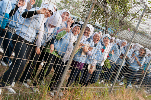大手日系企業の工場の鉄柵から、通りを行進するデモ隊に笑顔を送る女性労働者たち３日、西ジャワ州ブカシ県の東ジャカルタ工業団地