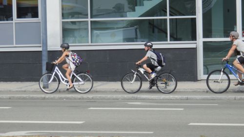 自転車で通学する生徒と後ろから見守る親