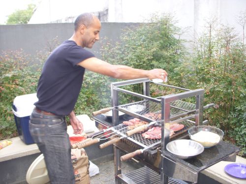 家族のシュラスコパーティーで自分たちで肉を焼く人（塩水をふりかけて味を付けている様子）