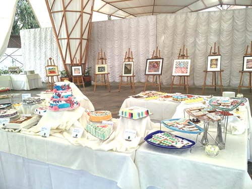 絵画の展示とアーティスティックにディスプレイされたスイーツのテーブル・