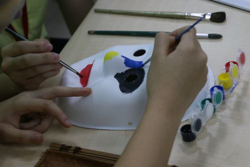 両校の生徒たちが共同作業で面具の色塗りを行います