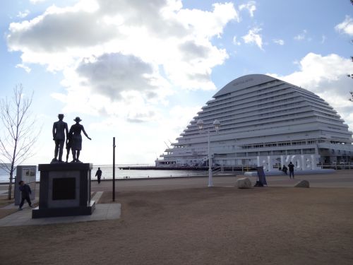 海を見つめる移民の親子像と隣接する神戸メリケンパークオリエンタルホテルと海を背景に「BE KOBE」の文字の置物