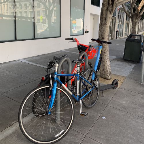 私物の自転車、シェアリングサービスの自転車、シェアリングサービスの電動キックスクーターが同じ場所にとめてあります。