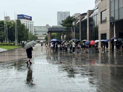 雨に濡れても並ぶ来場者